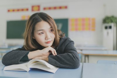 Asian woman looking away to the distance in front of a laptop